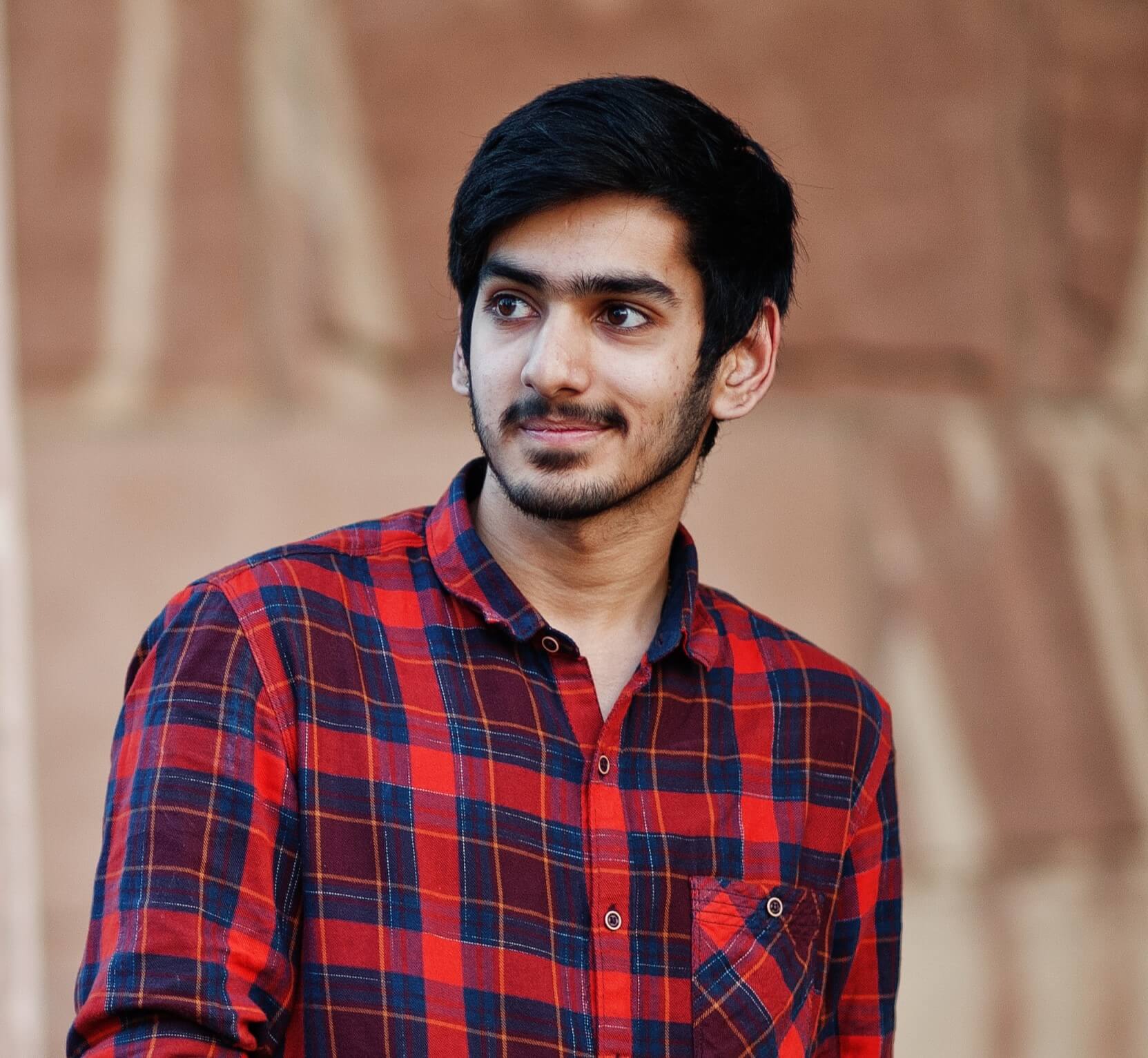 youngindianstudentmanredcheckeredshirtjeansposedcitywithmobilephonehands_qynzk_1663