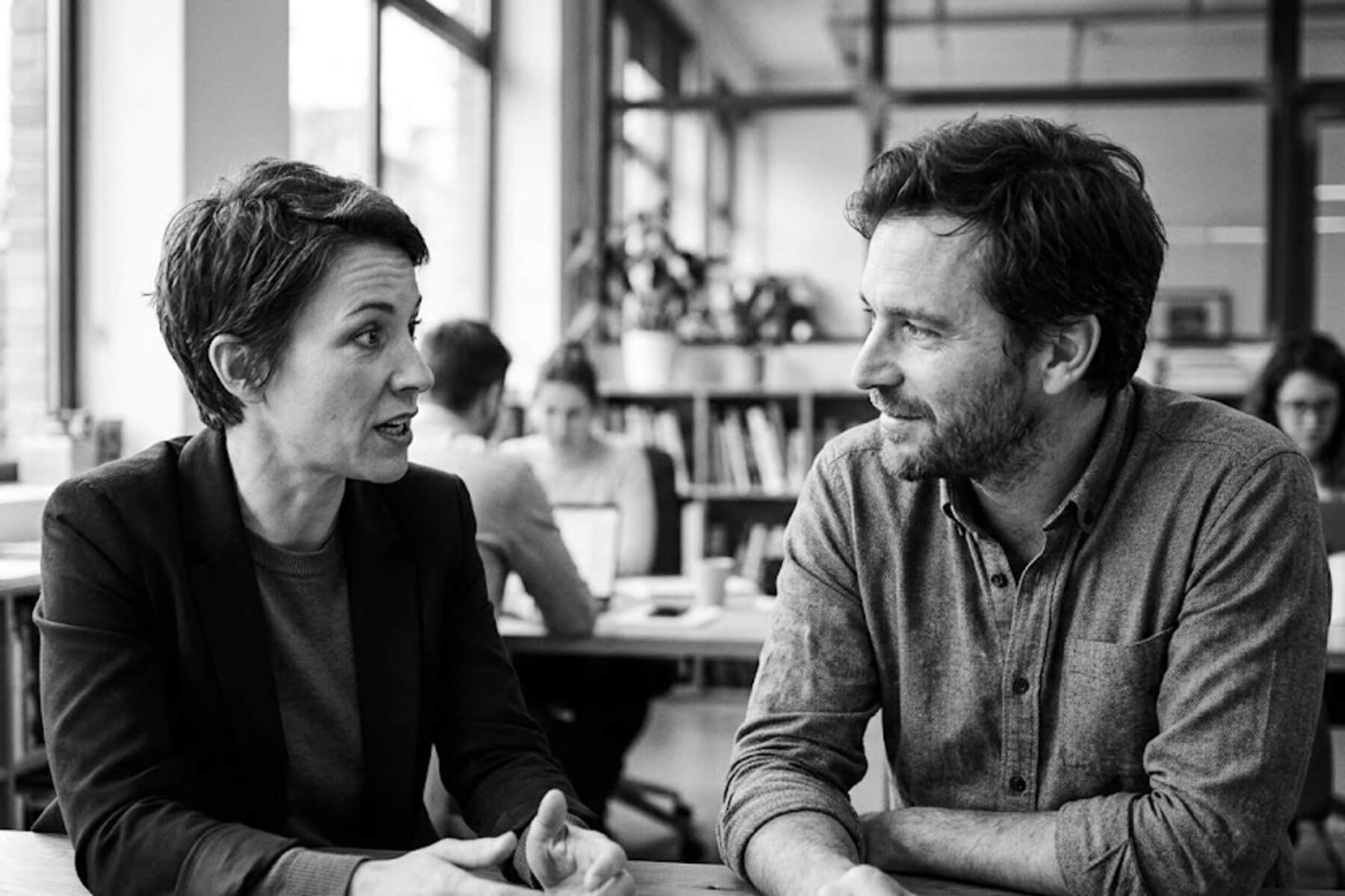 Black and white photo of a senior consulting executive mentoring a young professional, demonstrating training to replace yourself.